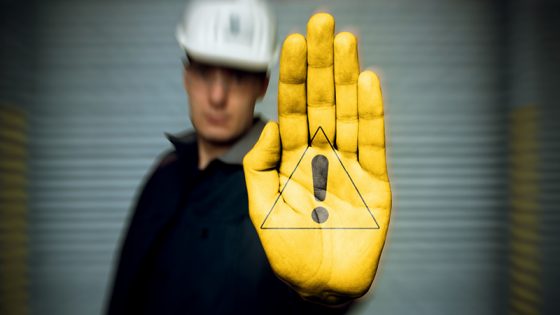 Mann in Sicherheitskleidung streckt seine gelb angemalte Hand mit einem Ex-Schutz Symbol nach vorne