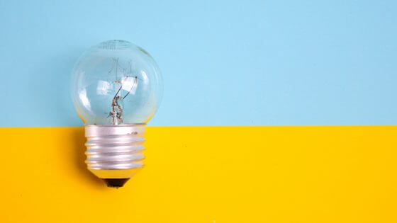 Glühbirne auf blau-gelbem Hintergrund - Symbol zur Ideenfindung